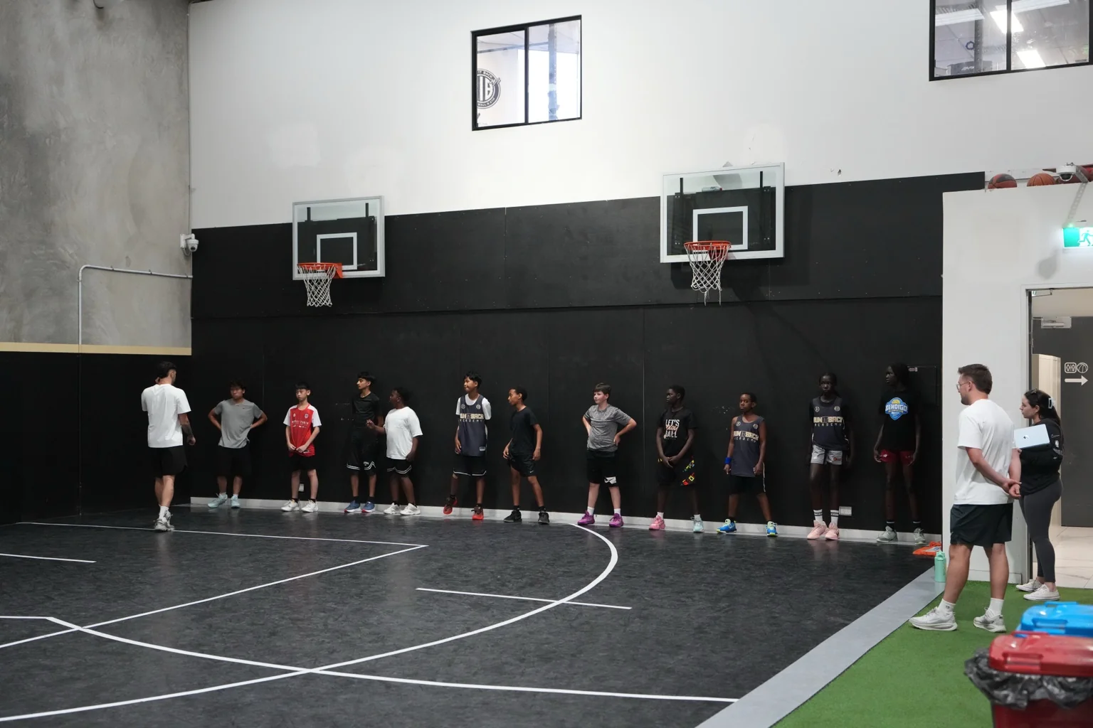 A youth Athletic Development group listening to their coaches on the RIB court
