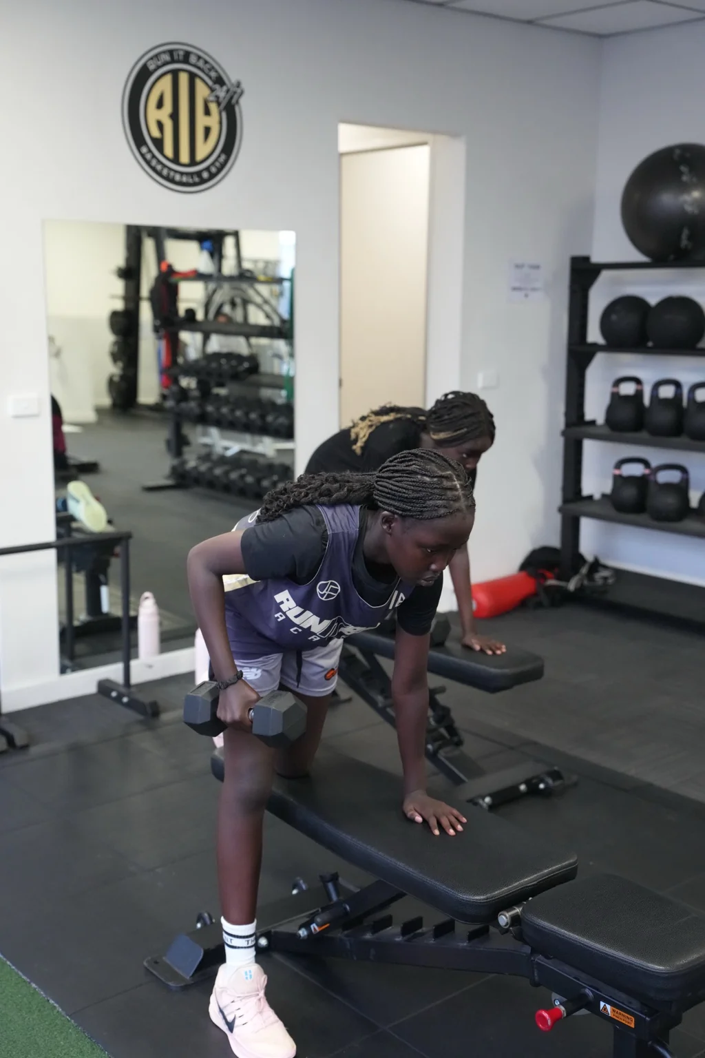 Young athletes practising dumbbell rows together at RIB